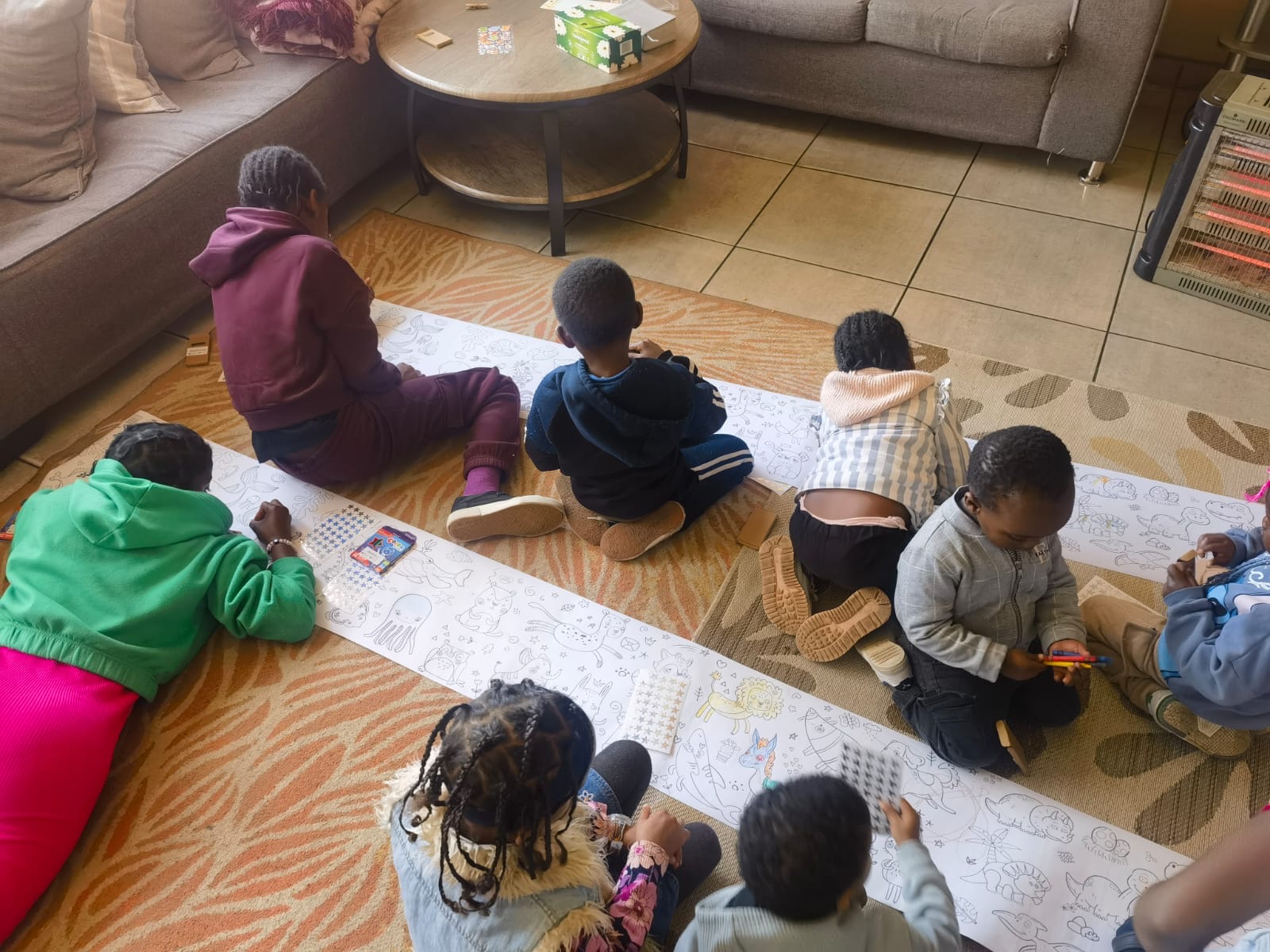 Children creating art together on a long roll of paper